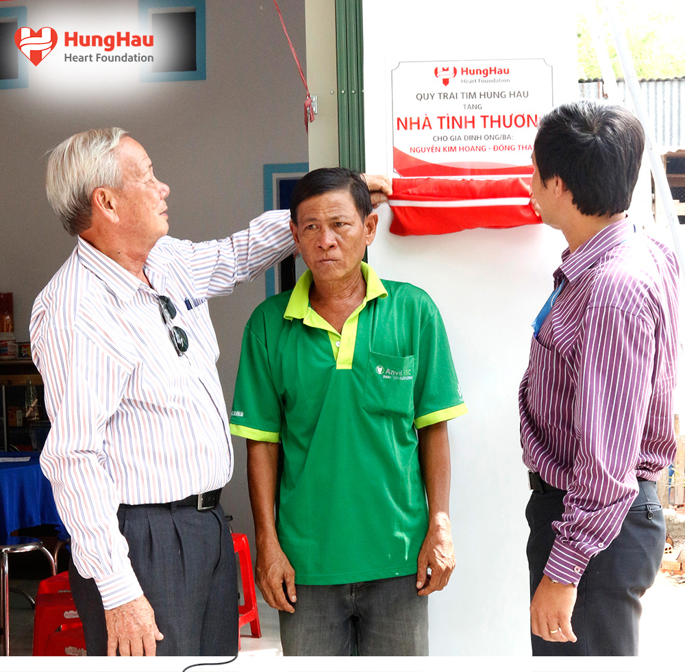 Thiếu tướng Trương Văn Thanh - Nguyên Phó Tư lệnh Bộ đội Biên phòng Việt Nam (bén trái) và ông Trần Quốc Trường - Giám đốc điều hành Quỹ Trái tim (bên phải) gỡ băng khánh thành nhà tình thượng trao tặng cho anh Nguyễn Kim Hoàng (đúng giữa)